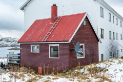 Rotes Häuschen vor großem Wohnblock